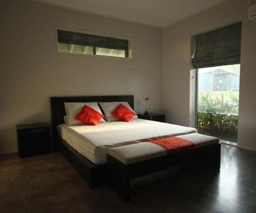 Maauga的住宿－一菲樂種植園度假屋，一间卧室配有一张带两个红色枕头的床