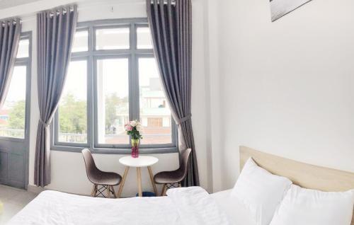 a bedroom with a bed and a table and a window at M Hotel Đà Lạt in Da Lat