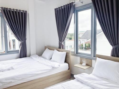 two beds in a room with two windows at M Hotel Đà Lạt in Da Lat