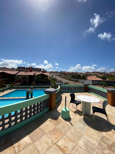 un patio con tavolo e sedie accanto alla piscina di Linda casa Porto das Dunas: 4 suítes, churrasqueira e piscina a Fortaleza