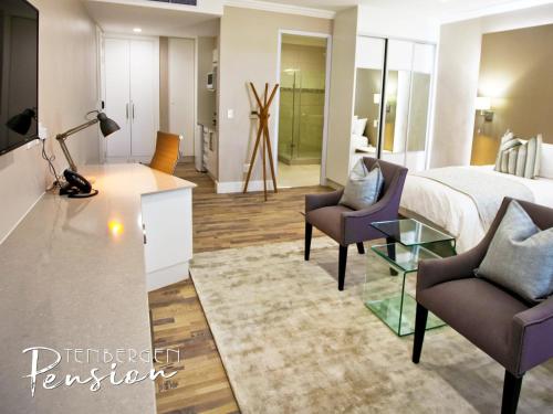 a hotel room with a bed and two chairs at Tenbergen Pension Hotel in Windhoek