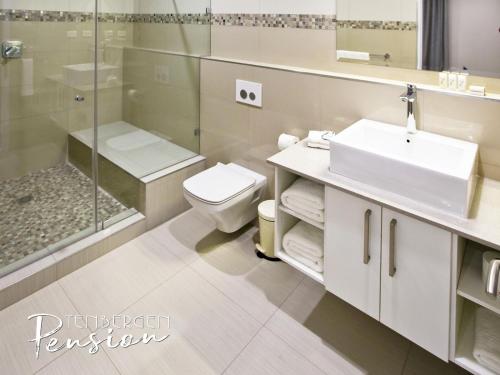 a bathroom with a sink and a toilet and a shower at Tenbergen Pension Hotel in Windhoek