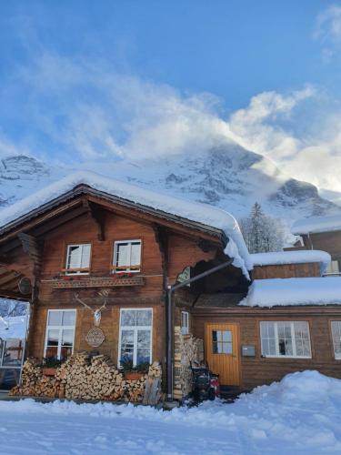 a house covered in snow with a mountain in the background at Jägerstübli Grindelwald in Grindelwald