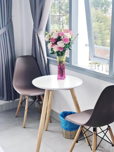 a vase of flowers sitting on a table with two chairs at M Hotel Đà Lạt in Da Lat