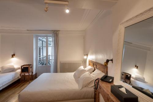 a bedroom with two beds and a mirror at Hôtel des Tonneliers in Beaune
