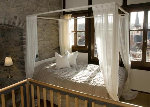 a bedroom with a canopy bed with white pillows at Jakobsturm Ferien im Turm in Röttingen
