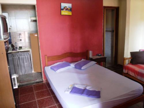 um quarto com uma cama branca e almofadas roxas em Suite BrisaMar em Cabo Frio