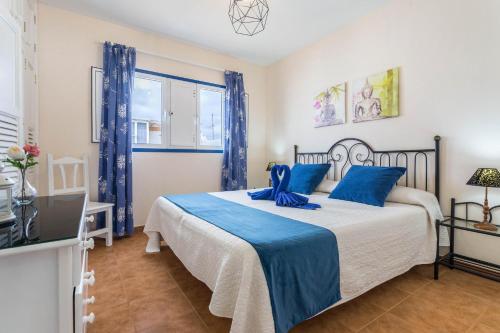 ein Schlafzimmer mit einem großen Bett mit blauen Kissen in der Unterkunft El Sombrerito 5 in Caleta de Sebo