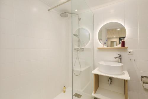 a white bathroom with a shower and a sink at Hotel Eemhof by Center Parcs in Zeewolde