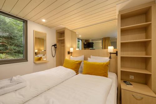 a bedroom with a large white bed with yellow pillows at Hotel Eemhof by Center Parcs in Zeewolde