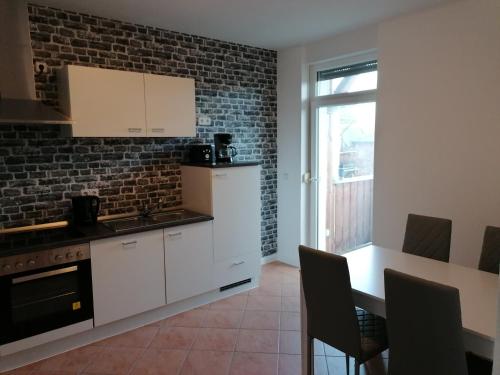 a kitchen with white cabinets and a brick wall at Apartment Bona Loca in Aschersleben