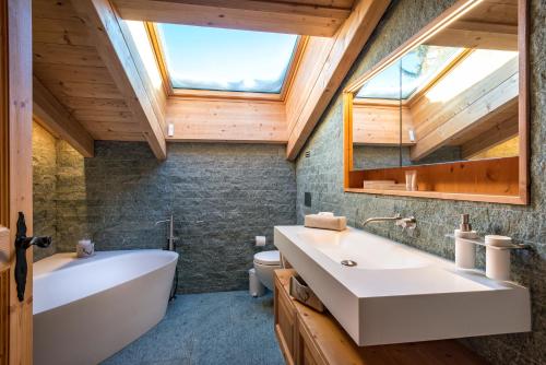 ein Badezimmer mit einem großen weißen Waschbecken und einem Dachfenster in der Unterkunft Hotel Sarain Active Mountain Resort in Lenzerheide