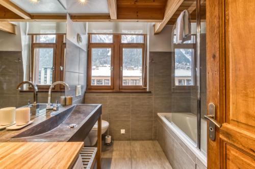 een badkamer met een wastafel, een bad en ramen bij Apartment Vila 2 Chamonix in Chamonix-Mont-Blanc