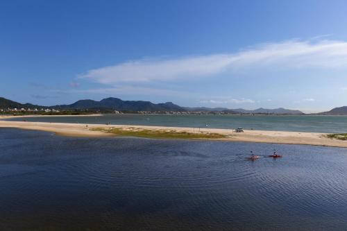 two people in boats in the water near a beach at Costa Norte Ponta das Canas Hotel in Florianópolis