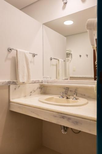a bathroom with a sink and a mirror at Costa Norte Ponta das Canas Hotel in Florianópolis