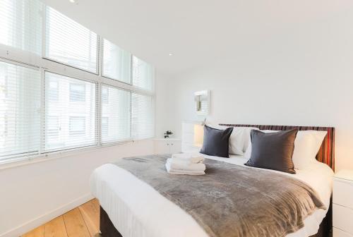 1 dormitorio blanco con 1 cama grande y ventanas en Trafalgar Square by Excel Apartments, en Londres