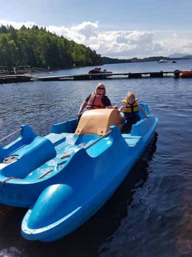 a woman and a child riding in an inflatable boat on the water at Insh Hall Rooms at Loch Insh in Kincraig