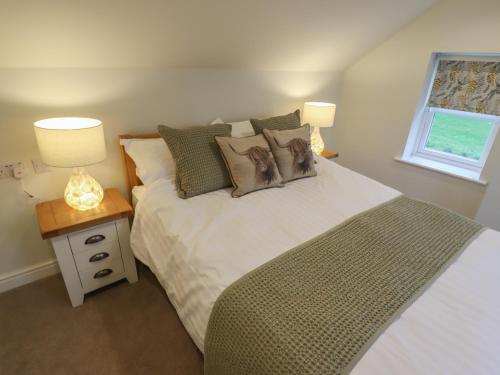 a bedroom with a bed with pillows and two lamps at Shepherd's Cottage in Alford