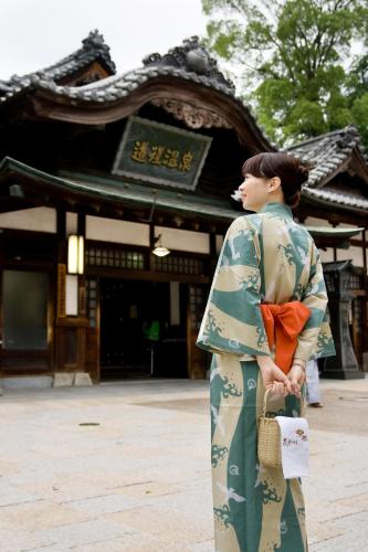 a woman in a kimono standing in front of a building at Dogo-no-Yado Katsuragi in Matsuyama