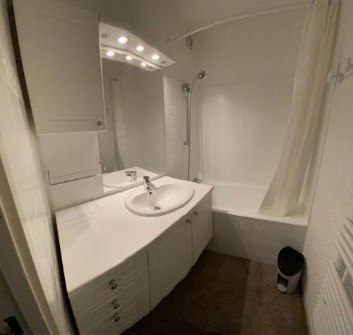 a white bathroom with a sink and a tub at Boost Your Immo Le Césier Risoul 411 in Risoul