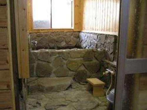 kamienna łazienka z kamienną wanną i oknem w obiekcie Matsunokitei Irori w mieście Otari