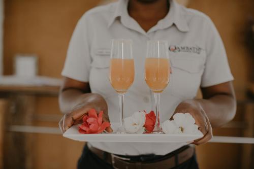 a man holding two champagne glasses and flowers on a plate at Qambathi Mountain Lodge in Kamberg Valley