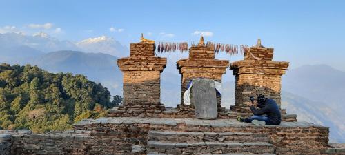 a man sitting on top of a stone monument with mountains in the background at Mochilero Ostello in Pelling
