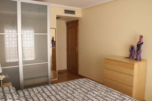 a bedroom with a bed and a dresser and a window at Amplio apartamento Plaza de Toros in Zaragoza