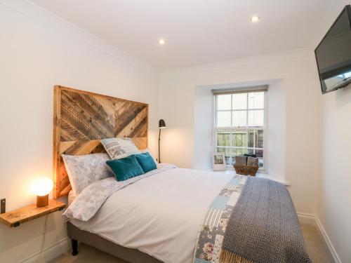 a bedroom with a large bed and a flat screen tv at Rhum Cottage in Cupar