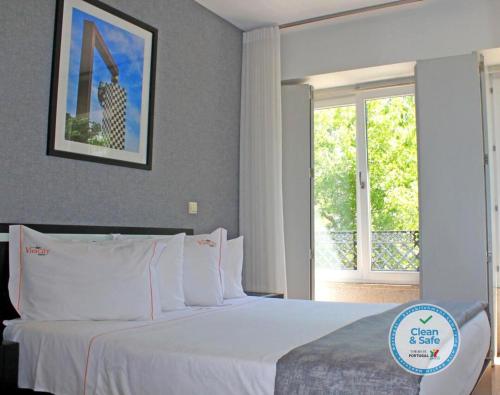 a white bed sitting in a bedroom next to a window at Vivacity Porto - Rooms & Apartments in Porto
