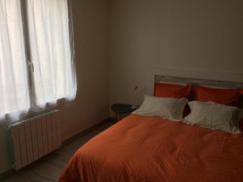 a bedroom with a bed with orange sheets and a window at La parenthèse in Saintes