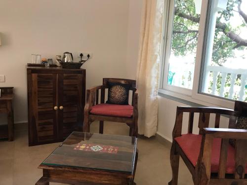 a living room with chairs and a table and a window at BaywoodGoa -200 meters from Morjim Beach in Morjim
