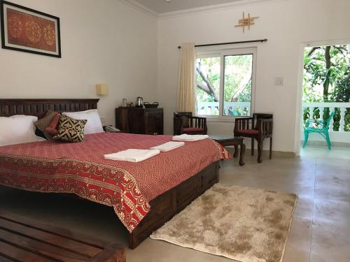 Schlafzimmer mit einem Bett mit einer roten Bettdecke in der Unterkunft BaywoodGoa in Morjim