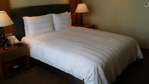 a hotel room with a large white bed with a phone at LOTTE City Hotel Daejeon in Daejeon
