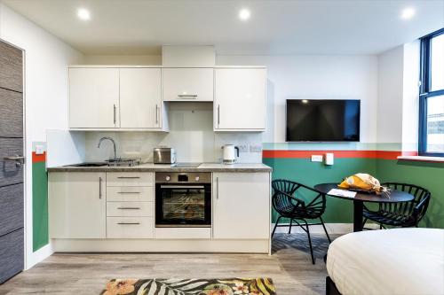 a kitchen with white cabinets and a table and a tv at Your Apartment I Clifton Village in Bristol