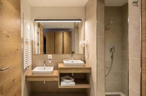 a bathroom with two sinks and a shower at Hotel Restaurant Schaurhof in Vipiteno