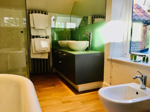 a bathroom with a sink and a mirror and a tub at Felbrigg Lodge Bed And Breakfast in Aylmerton