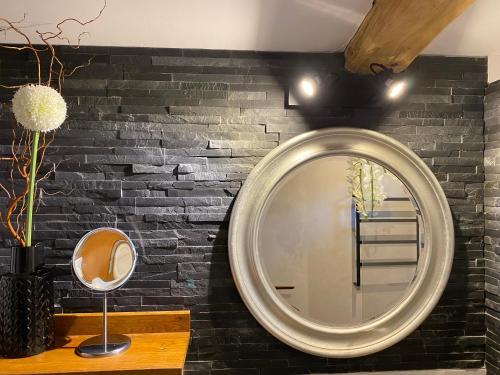 La salle de bains est pourvue d'un miroir rond sur un mur en briques. dans l'établissement Le Maskalou, à La Colle-sur-Loup