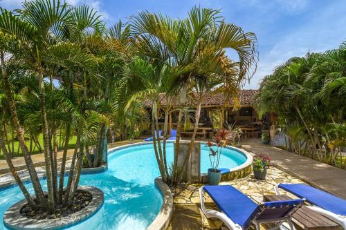 a swimming pool with palm trees and blue chairs at Casa Lajagua in Pedasí Town