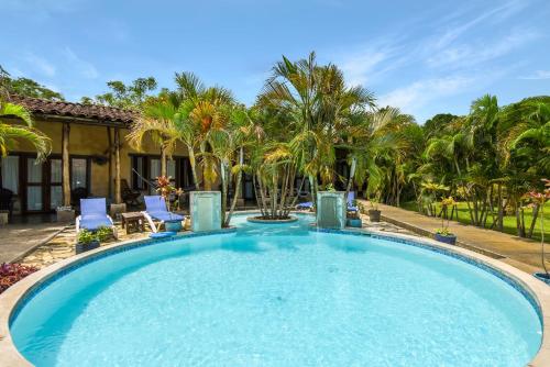 a large swimming pool with blue chairs and palm trees at Casa Lajagua in Pedasí Town