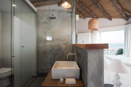 a bathroom with a sink and a shower and a toilet at MarAdentro Apart Hotel & Suites in Punta Del Diablo