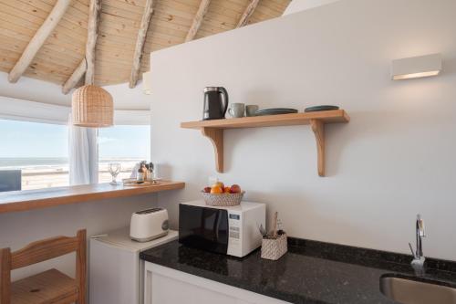 a kitchen with a counter with a microwave and a window at MarAdentro Apart Hotel & Suites in Punta Del Diablo