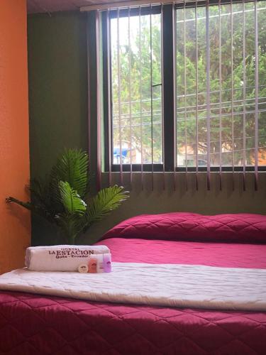 a bedroom with a bed with a red blanket and a window at Hostal La Estación Quito in Quito