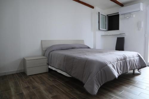 a white bedroom with a bed and a night stand at La Bellavista Mola di Bari in Mola di Bari