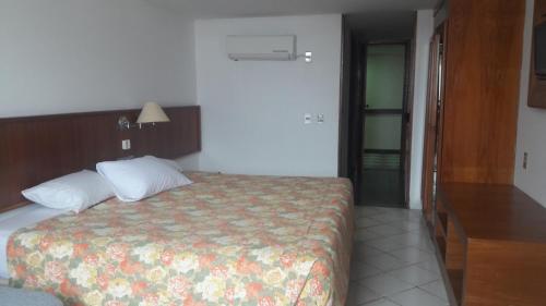 um quarto com uma cama com colcha floral em Apart Hotel Sol Vitória Marina em Salvador