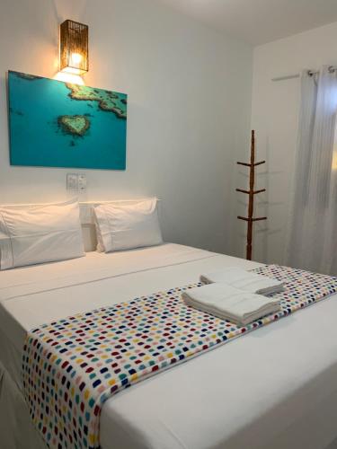 Una cama blanca con una manta de colores. en Pousada Du’Forte en Praia do Forte