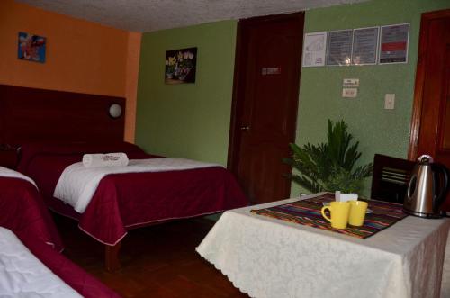 a hotel room with two beds and a table with cups on it at Hostal La Estación Quito in Quito
