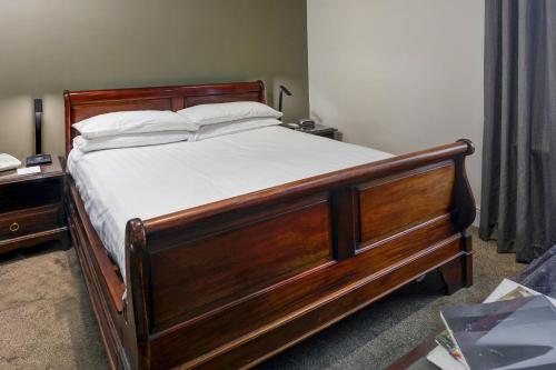 a bedroom with a wooden bed with white sheets and pillows at Best Western Claydon Hotel in Ipswich