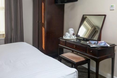 a bedroom with a desk with a mirror and a bed at Best Western Claydon Hotel in Ipswich