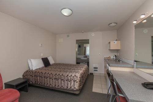 a bedroom with a bed and a kitchen with a sink at Bella Vista Motel Fox Glacier in Fox Glacier